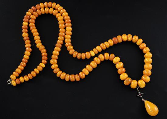 A single strand graduated disc shaped amber bead necklace with rose cut diamond and ruby set amber drop pendant, gross weight